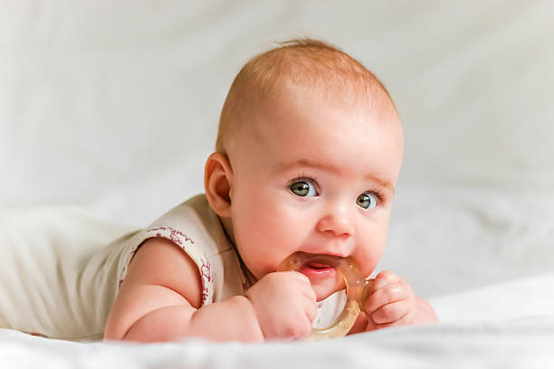 a cute baby biting on a teething toy