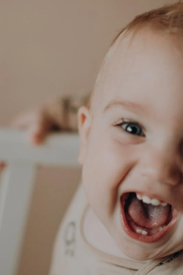  a close-up photo of a cute baby showing his teeth