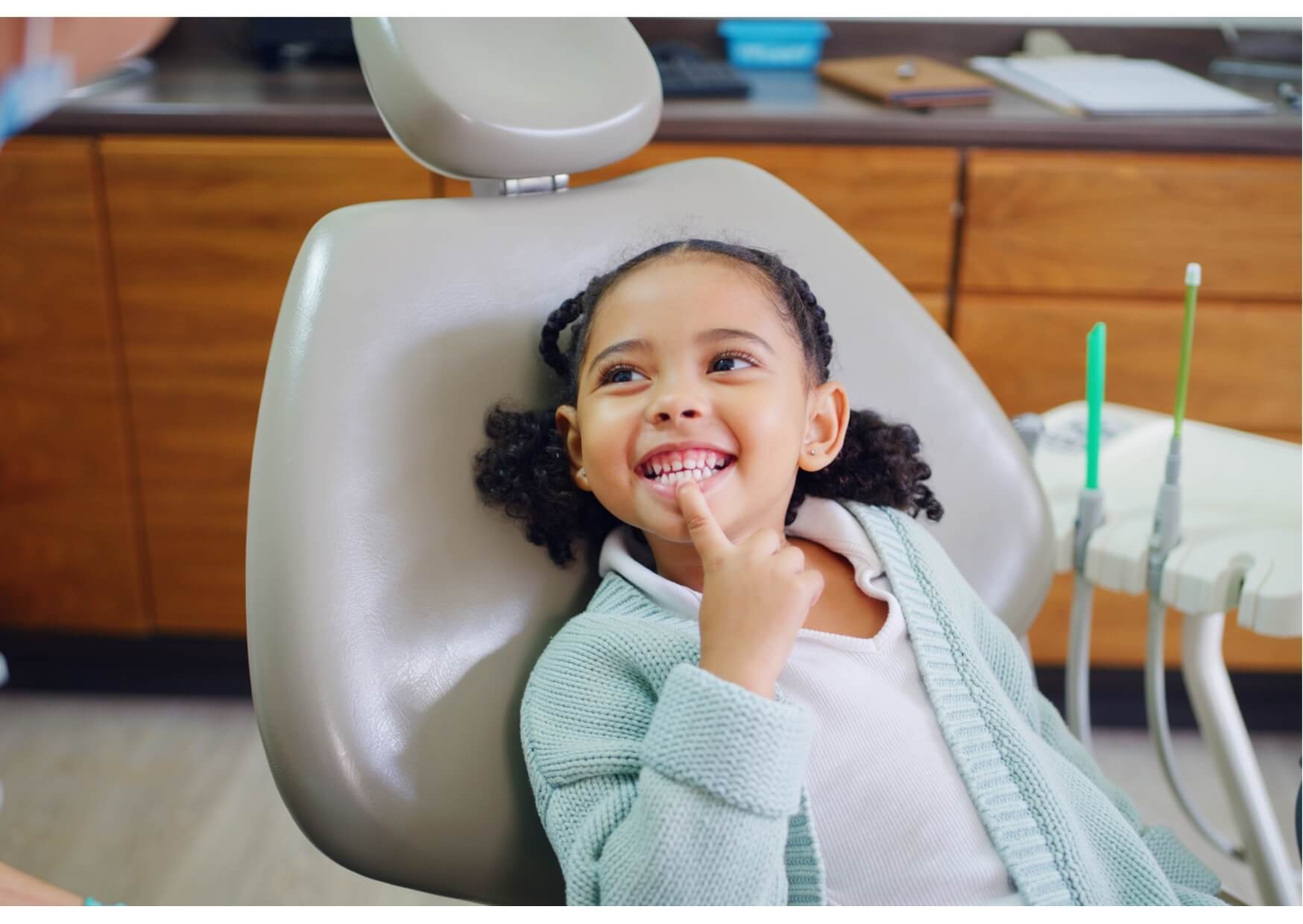 Young child smiling in a dental chair during a relaxed first dental appointment and routine checkup