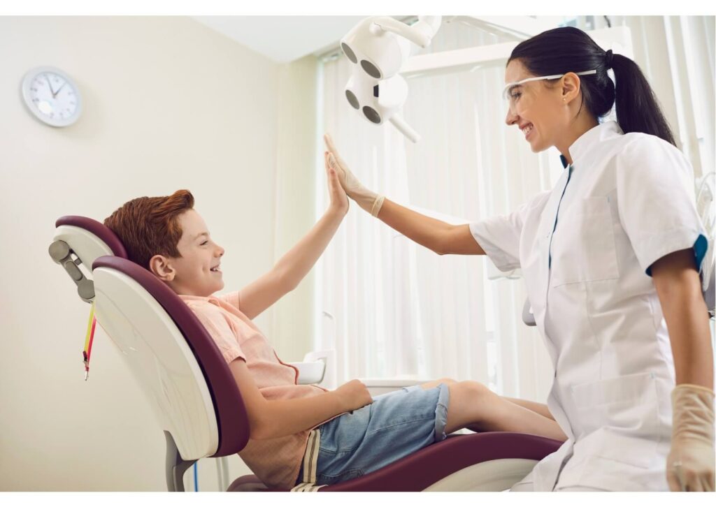 Child giving a high five to a dentist during a comfortable and positive first dental appointment