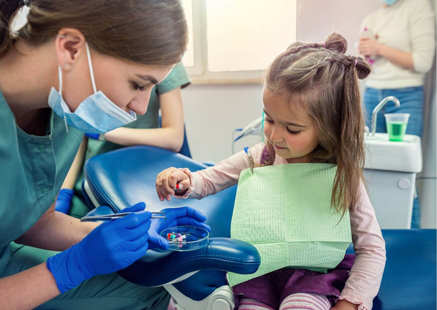 Pediatric dental professional helping a young child feel comfortable during a dental visit, demonstrating when to start regular dental checkups for children.