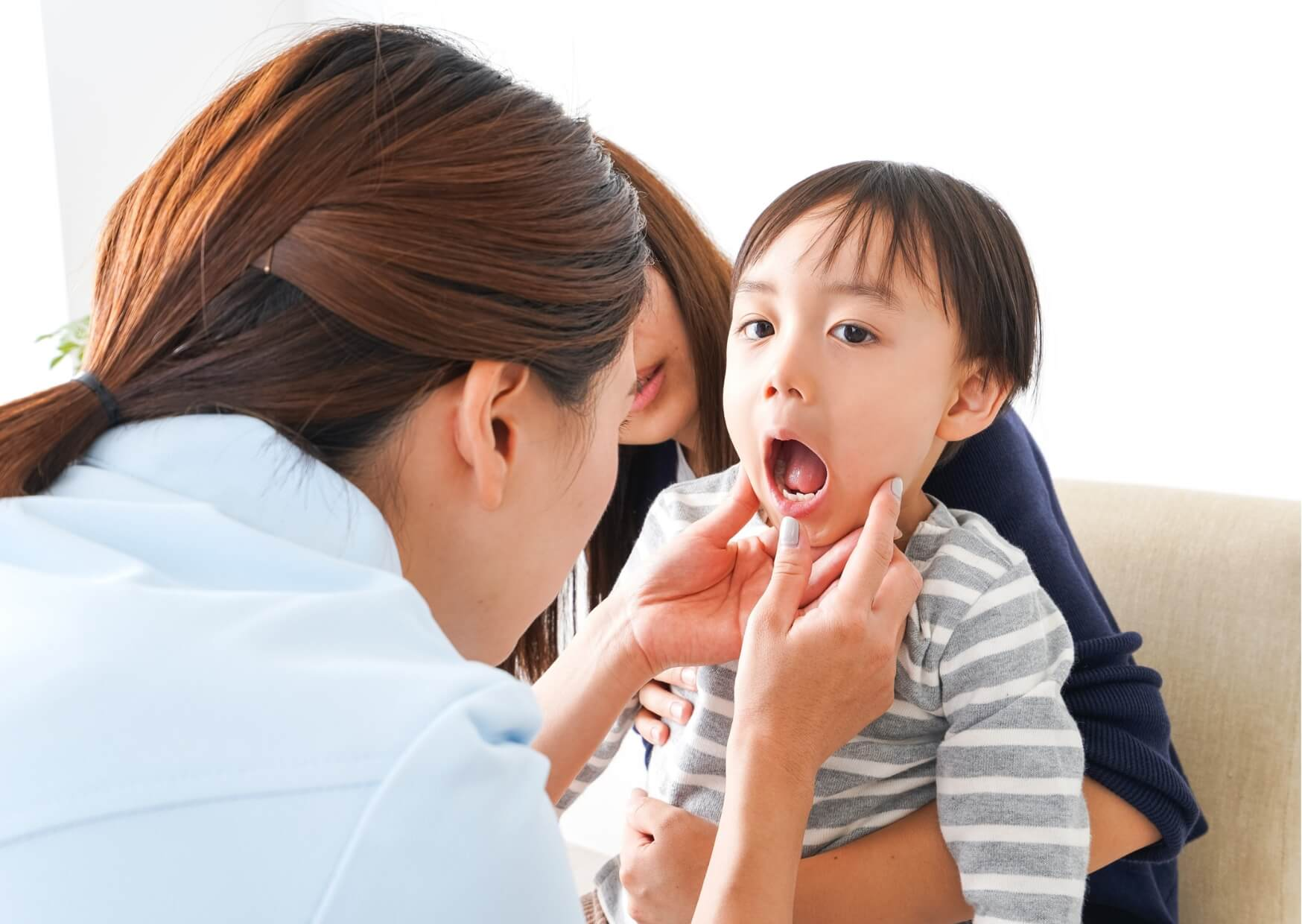 Dentist checking a young child's mouth during a pediatric dental exam to determine if a kids dental spacer may help preserve space for permanent teeth.